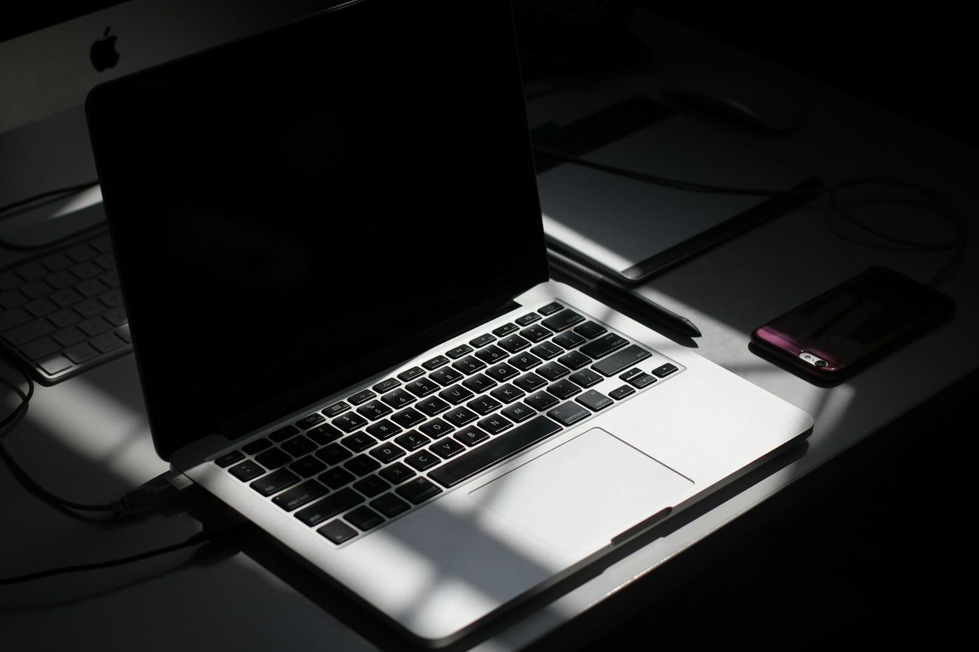 Mesa de trabalho com notebook, cartões de visita e celular